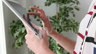 一个女人站在办公室时使用数字平板电脑的手。